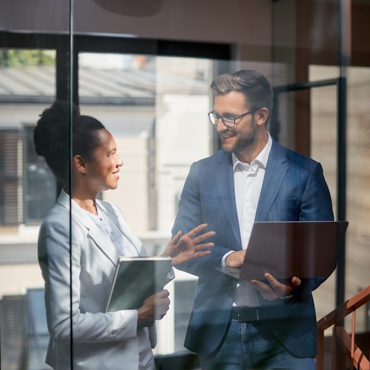 Zwei Kolleginnen und Kollegen im Gespräch in einem modernen Büro